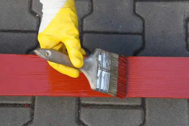Persona pintando una linea roja anticorrosivos-asteclub