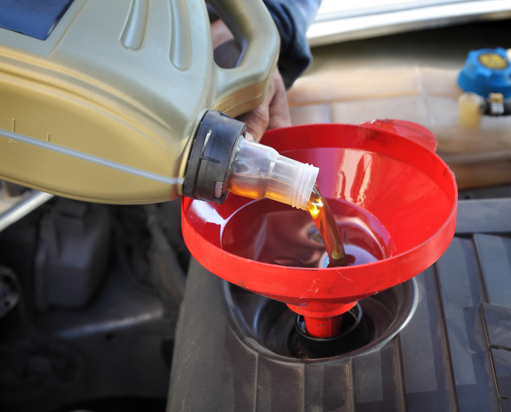 Hombre aplicando lubricante automotriz con embudo-asteclub