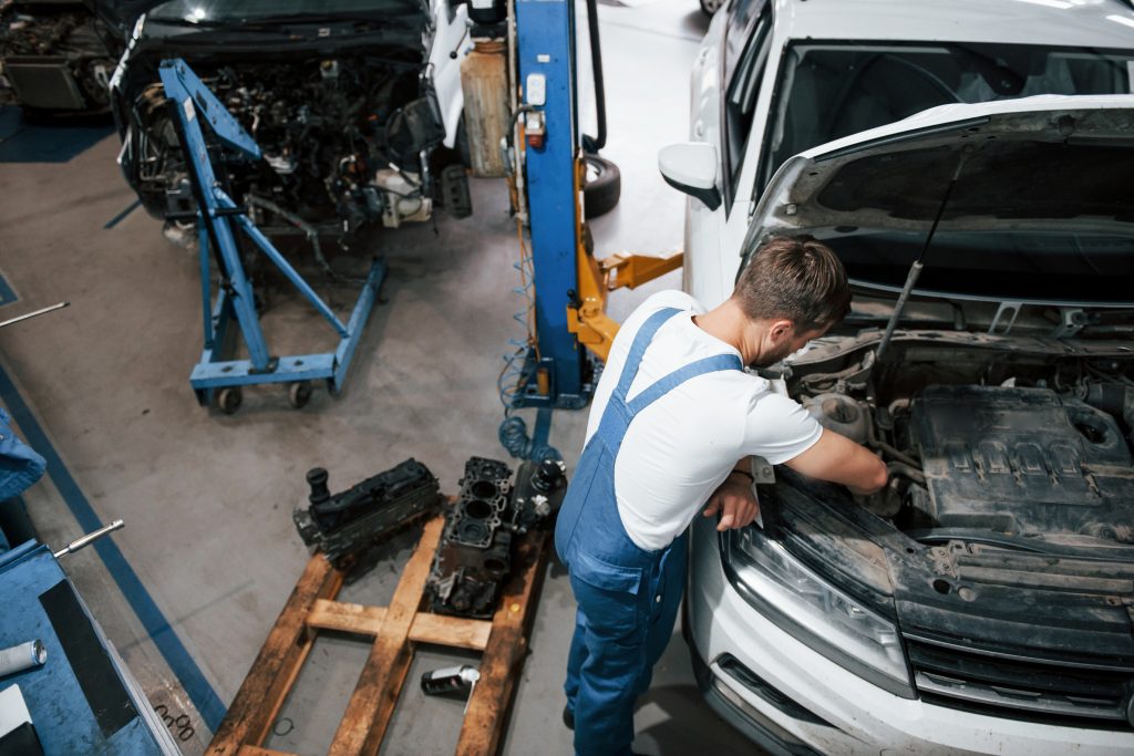 Mecánico automotriz realizando mantenimiento a un motor-asteclub